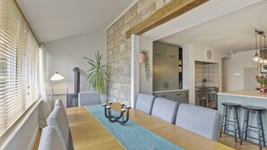 A dining area with a wooden table, grey upholstered benches, and a blue placemat. - Wyndgrove House - North East Escapes (Seahouses)