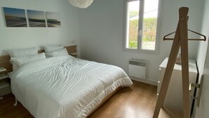 Quarto com cama, mesas de cabeceira, cômoda, janela e luminária pendente.