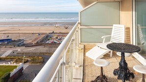 A balcony with a view of the beach, a table, and two chairs. - Apartment with Terrace and Parking in Le Touquet (Le Touquet-Paris-Plage)
