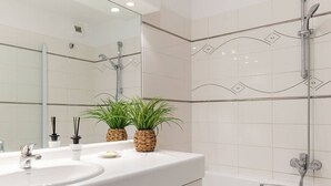 A modern bathroom with a white vanity, a large mirror, two potted plants, and a shower area. - Apartment with Terrace and Parking in Le Touquet (Le Touquet-Paris-Plage)
