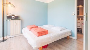 Ein Schlafzimmer mit einem Bett, Kissen, einem Heizkörper, einer Lampe und einem Kleiderschrank.