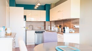 Eine moderne Küche mit weißen Schränken, einem Geschirrspüler, einer Kaffeemaschine und einem Toaster.