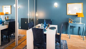 A modern dining area with a white table, dark chairs, and a blue wall. - Apartment with sea side view, city center (Le Touquet-Paris-Plage)