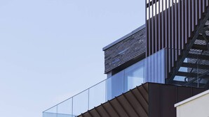 A modern building with a glass balcony and a metal staircase.