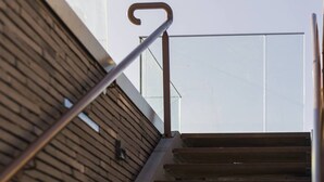 A metal staircase with wooden steps leading upwards, adjacent to a building with a wooden facade.