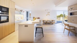 A modern kitchen with a central island, built-in appliances, and a dining area with a view.
