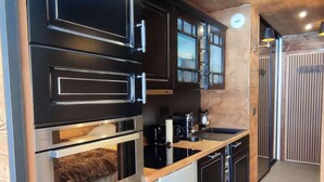 A modern kitchen with black cabinets, stainless steel appliances, and a wooden countertop. - Cozy studio at the foot of the slopes with terrace (Isola 2000)