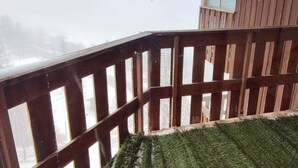 A wooden deck with a railing, a window, and a view of a snowy landscape. - Cozy 2-room near slopes at Isola 2000 (Isola 2000)