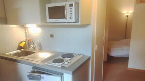 A compact kitchen with a microwave, sink, and built-in oven. - Cozy 2-room near slopes at Isola 2000 (Isola 2000)