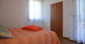 Un dormitorio con cama, un armario de madera y cortinas con motivos florales.