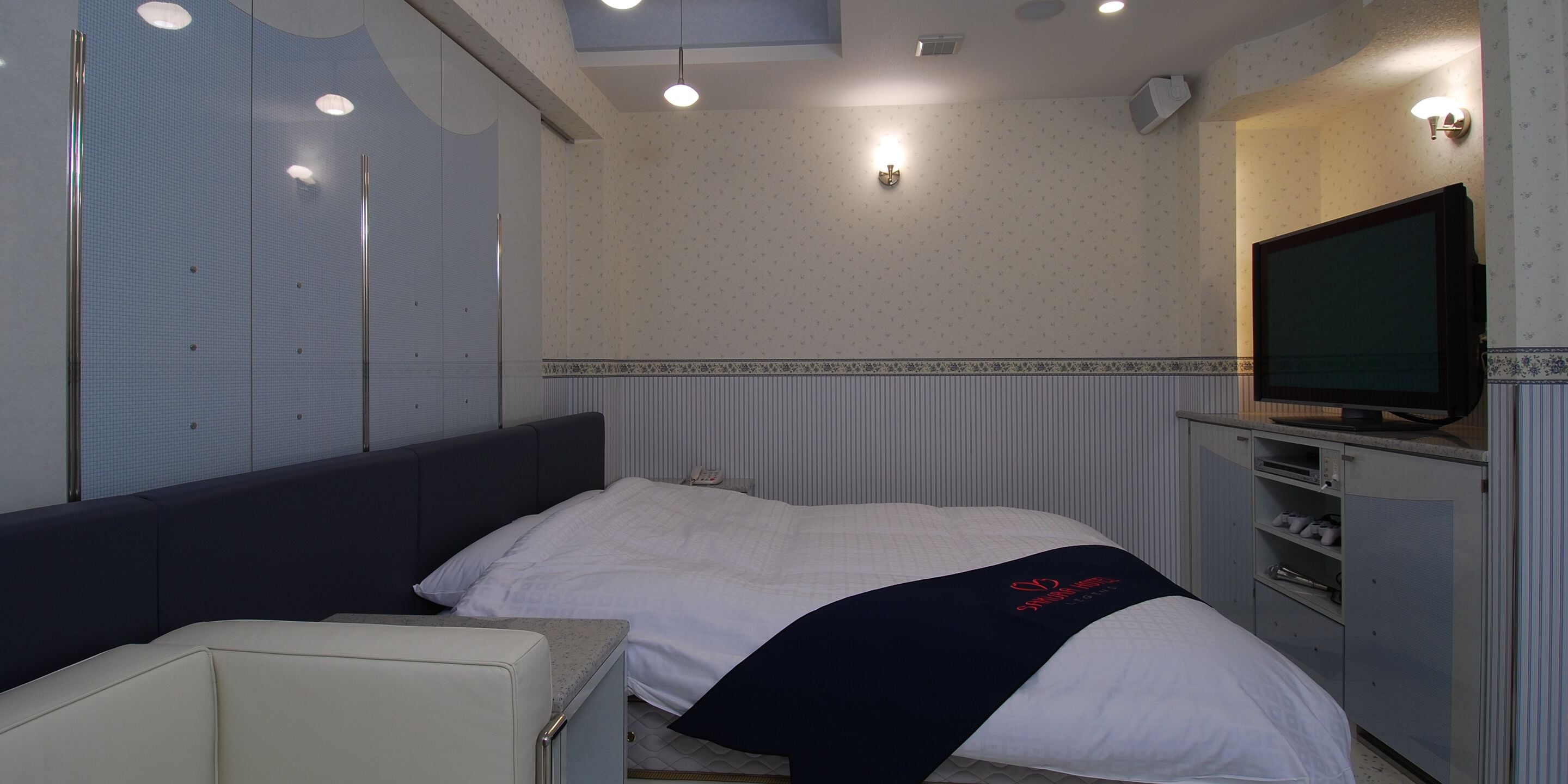 A hotel room with a bed, a TV, a desk, and a chair.