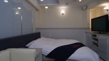A hotel room with a bed, a TV, a desk, and a chair.