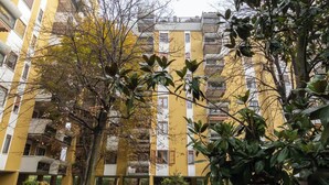 A multi-story yellow building with balconies, surrounded by trees and a small lawn. - Moncler House Navigli (Milano)