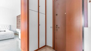 A room with a white sofa, a wardrobe with a wooden finish, and a white cabinet. - Moncler House Navigli (Milano)