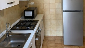 A kitchen with a gas stove, a microwave, a stainless steel sink, and a refrigerator. - George Penthouse Palermo (Palermo)