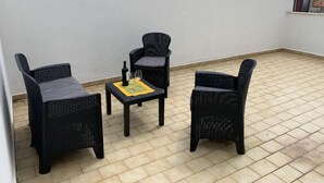 A small outdoor seating area with three wicker chairs and a table, featuring a bottle and glass. - George Penthouse Palermo (Palermo)