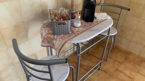 A small dining area with a table and two chairs, a coffee maker, a basket of bread, and a salt shaker. - George Penthouse Palermo (Palermo)