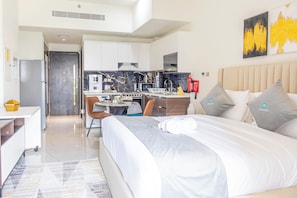 A modern hotel room with a large bed, a desk, and a kitchenette. - Bloomfields Elegant STU Jewelz (Dubai)