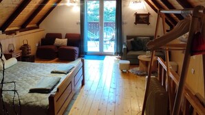 Un dormitorio en el ático con piso de madera, una cama, un sofá y una escalera.