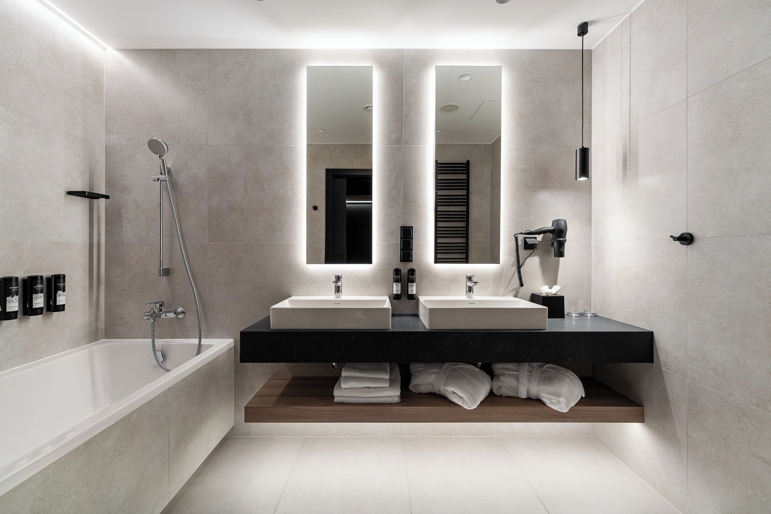 Ein modernes Badezimmer mit einer großen Badewanne, zwei Waschbecken und einem Spiegel über den Waschbecken.