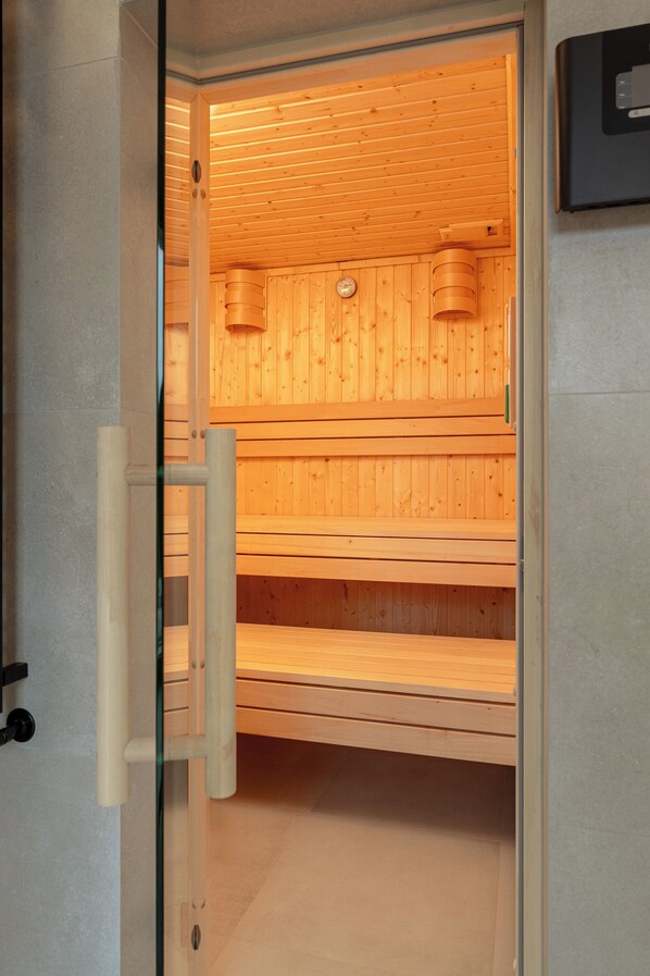 Una sauna con bancos de madera y una puerta de vidrio.