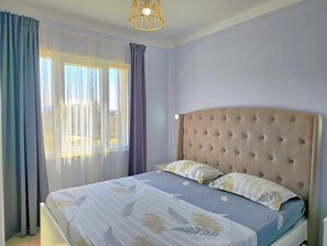 Un dormitorio con cama, cortinas y una lámpara colgante.