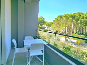 Un balcón con una mesa y dos sillas, con vistas a un paisaje verde con árboles y una carretera.