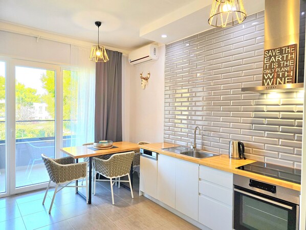 A modern kitchen with a brick backsplash, a built-in oven, and a dining area with chairs and a table.