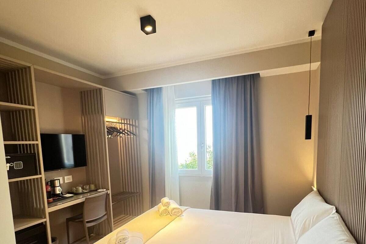 Een hotelkamer met een bed, bureau, televisie en een raam met gordijnen.
