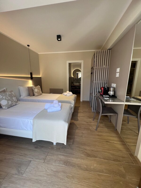 A hotel room with two beds, a desk, and a shower area.