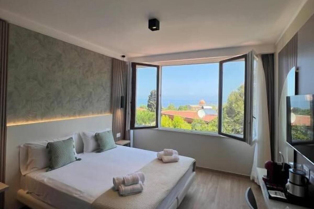 Een moderne hotelkamer met een groot bed, een bureau en uitzicht op zee.