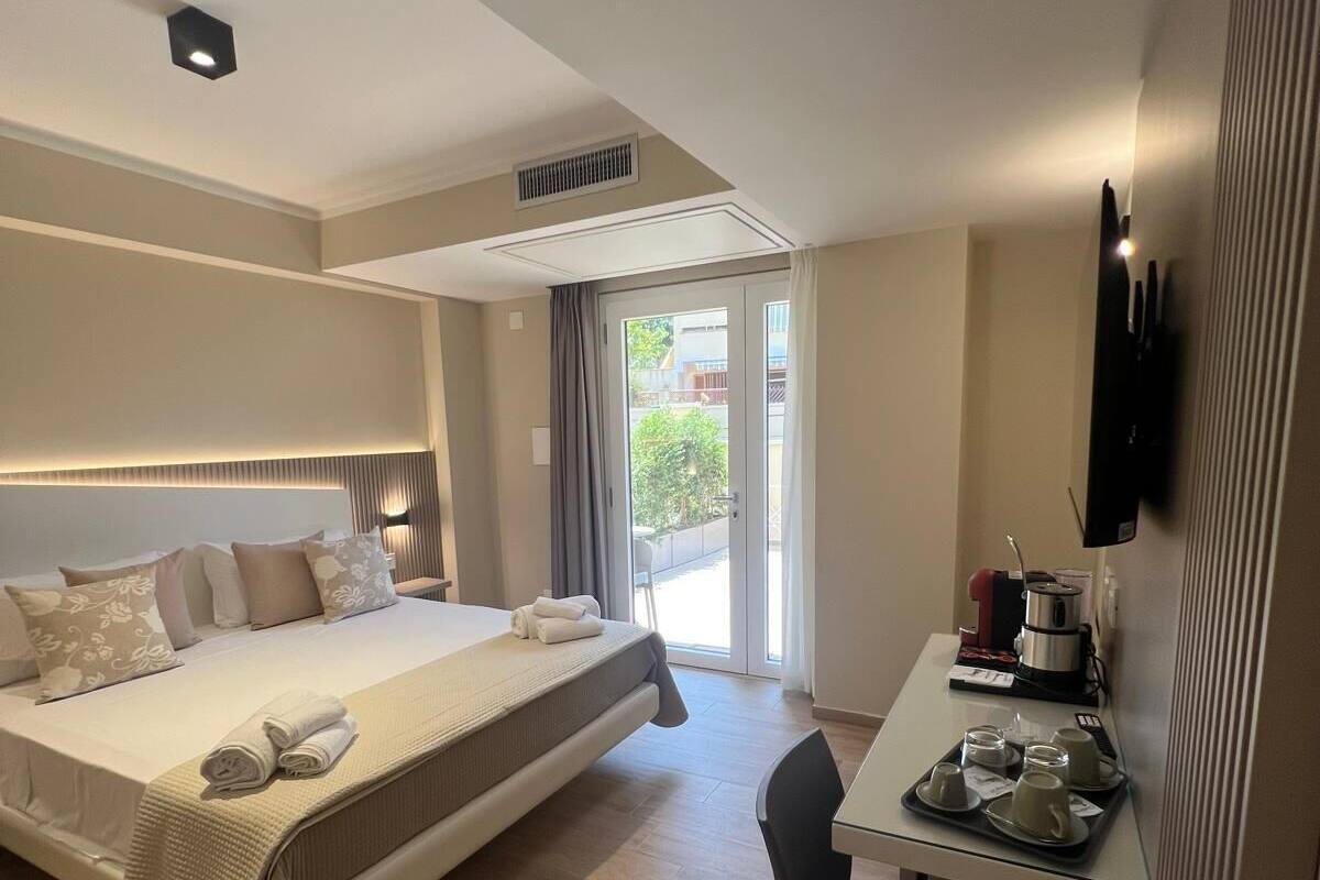 Hotelkamer met een bed, een bureau met een dienblad met kopjes en een waterkoker, en een televisie aan de muur.