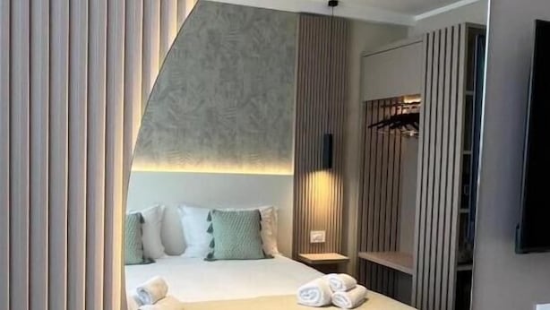 A modern hotel room with a large mirror, a neatly made bed, a bedside table, and a small seating area. - Residenza Gurnea - Free Private Parking (Tropea)