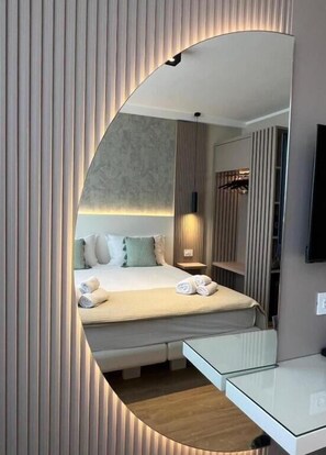 A modern hotel room with a large mirror, a neatly made bed, a bedside table, and a small seating area. - Residenza Gurnea - Free Private Parking (Tropea)