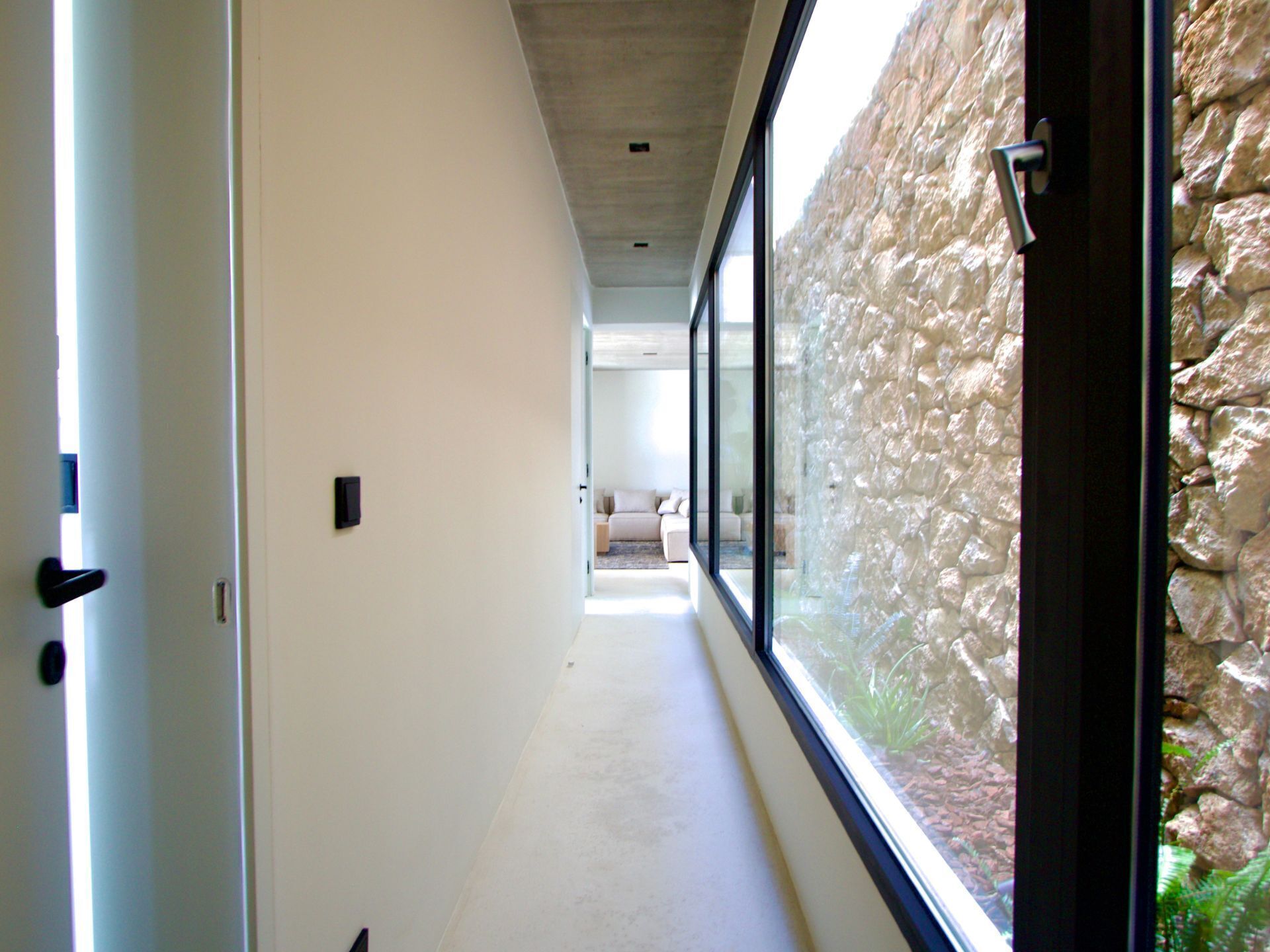 Un couloir moderne avec un mur en pierre et de grandes fenêtres.
