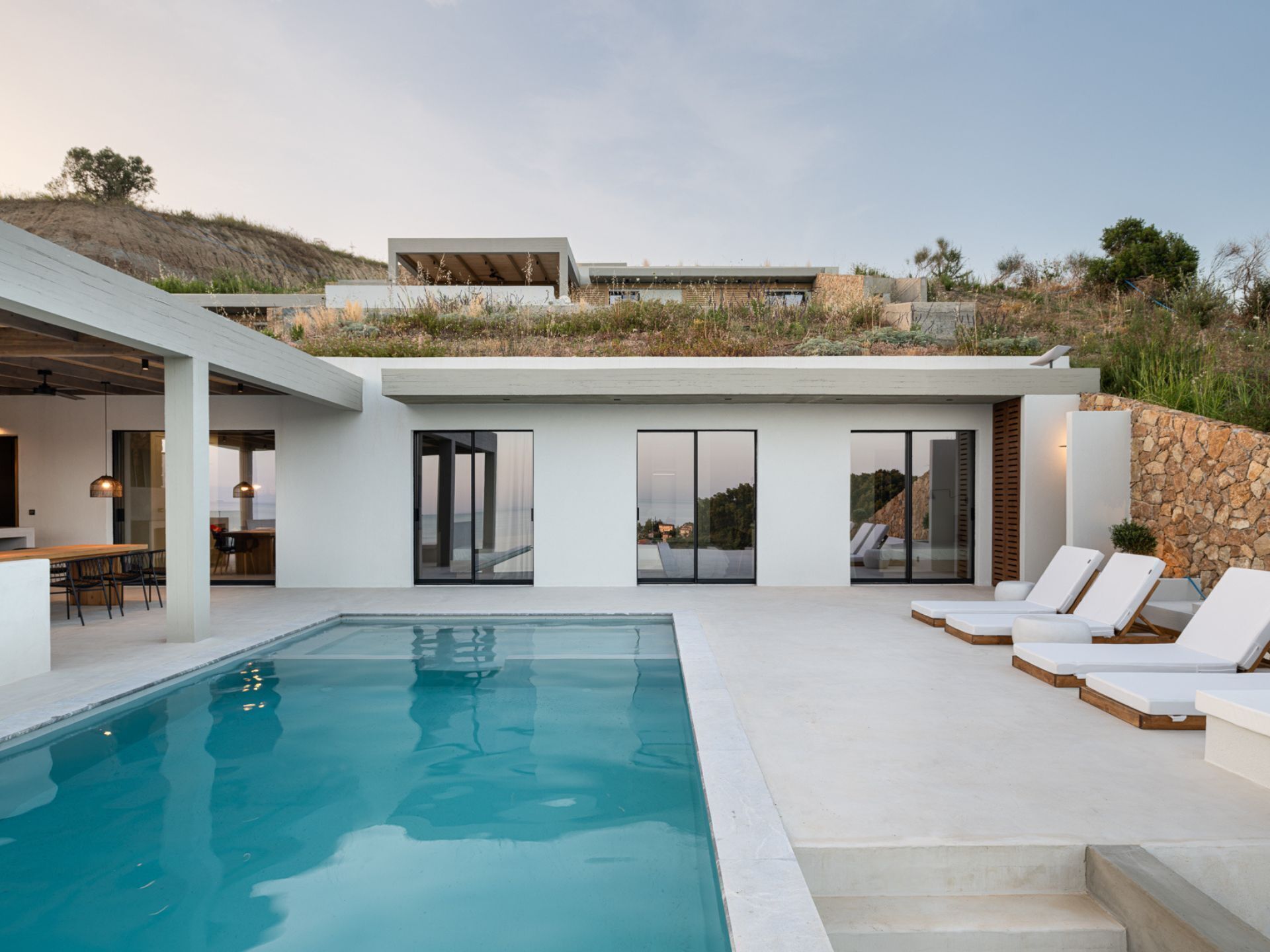 Une maison moderne dotée d’une piscine, d’un espace extérieur aménagé et offrant une vue sur le paysage environnant.