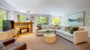 A modern living room with a fireplace, a large sofa, a coffee table, and a television.