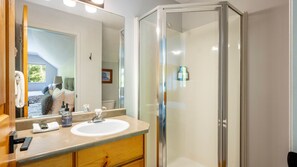 A modern bathroom with a glass shower enclosure, a sink with a mirror, and a towel rack.