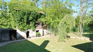 A rustic building with a wooden balcony, surrounded by lush greenery and a fenced yard. - Holiday Home Saniv (Batina)