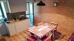 A kitchen with white cabinets, a wooden countertop, and a red and white checkered tablecloth-covered dining table with four chairs. - Holiday Home Saniv (Batina)