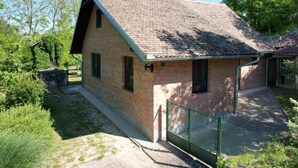 A small brick building with a sloped roof, a fenced area, and a paved walkway leading to it. - Holiday Home Saniv (Batina)
