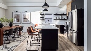 A modern kitchen with a central island, stainless steel appliances, and a dining area with a wooden table and chairs. - Copper Pointe | Lake view, Hot tub, Theatre, Pool table, Dog-friendly (Hollister)