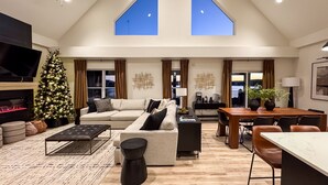 A spacious living room with a high ceiling, a fireplace, a Christmas tree, and a dining area with a table and chairs. - Copper Pointe | Lake view, Hot tub, Theatre, Pool table, Dog-friendly (Hollister)