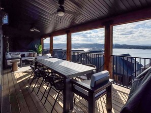 Eine überdachte Terrasse mit Tisch und Stühlen, einer Couch und einem Blumentopf.