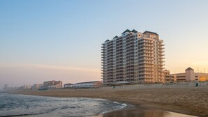 Un hotel moderno de gran altura con múltiples balcones, situado junto a la playa.