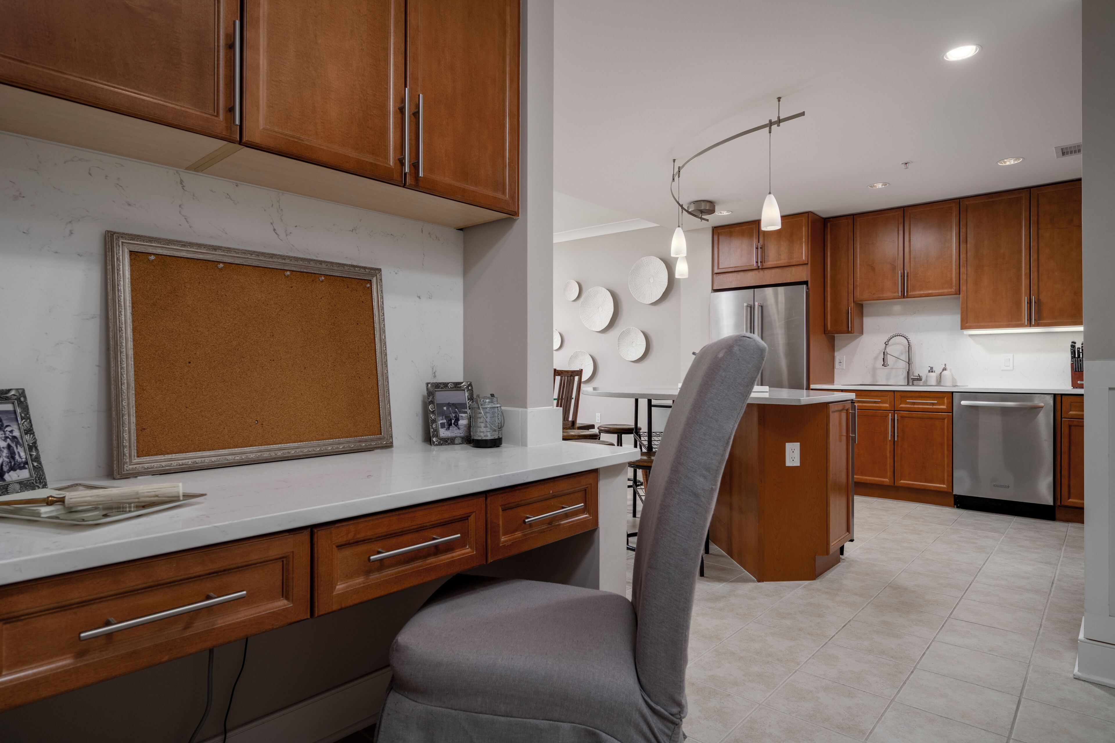 A modern kitchen with wooden cabinets, a marble countertop, and a grey chair.