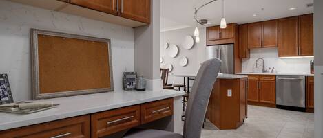 A modern kitchen with wooden cabinets, a marble countertop, and a grey chair.