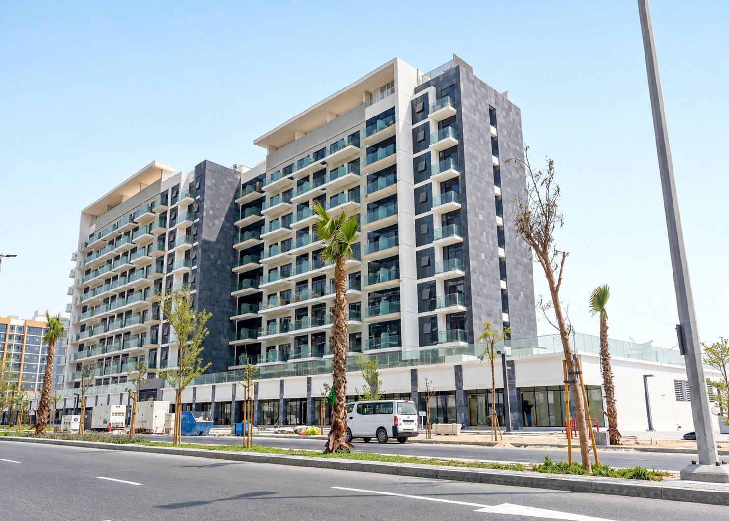 A multi-story hotel with balconies, a parking area, and a clear sky.
