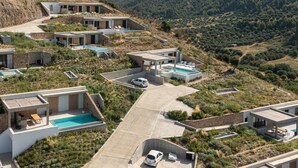 A modern resort with multiple buildings, swimming pools, and a hilly landscape in the background. - Design Villa Skioni by Halkidiki Villas (Kassandra)