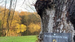 A welcome sign attached to a tree in a natural setting.